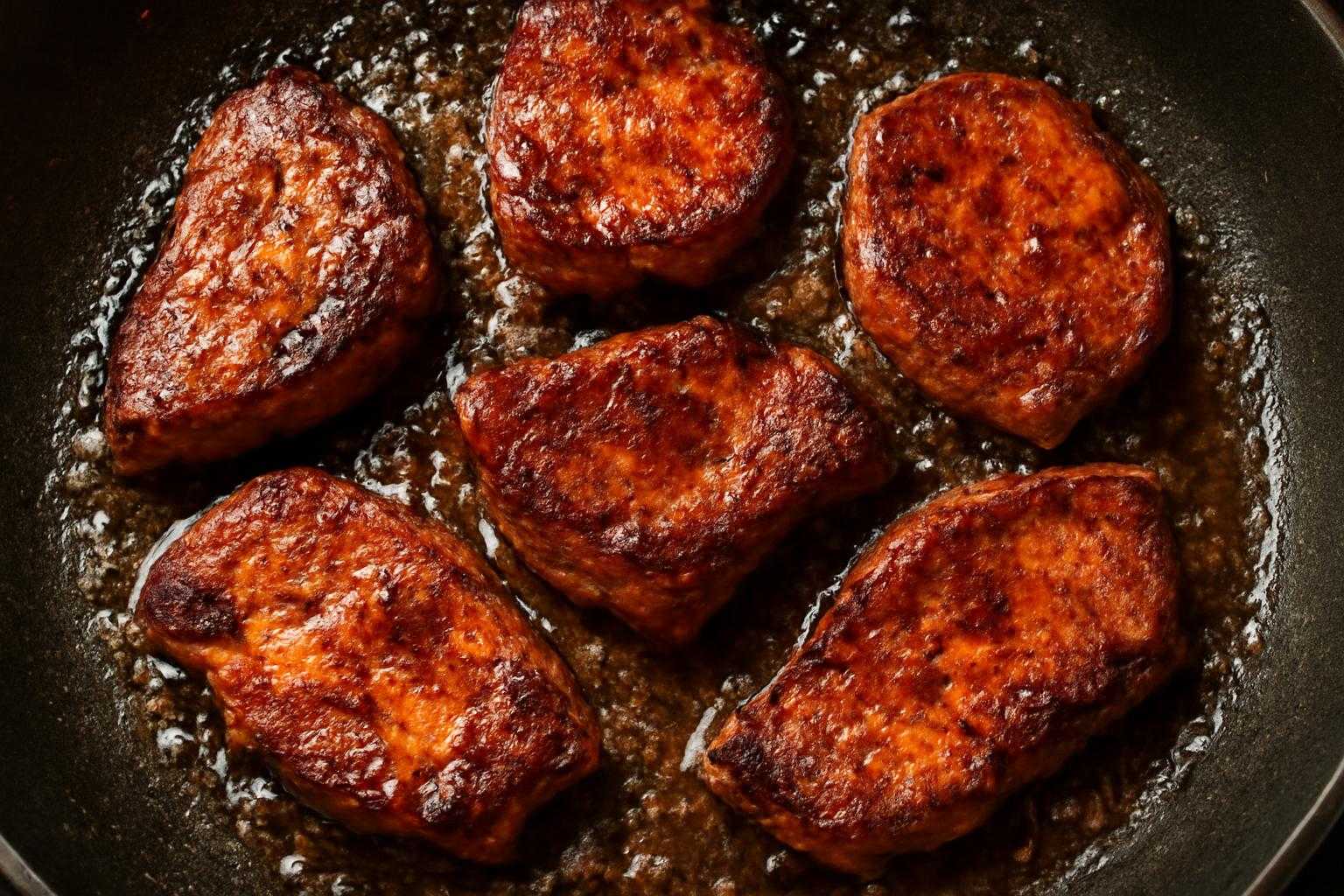 フライパンで肉を焼く際の温度管理と焼き方を示すイメージ
