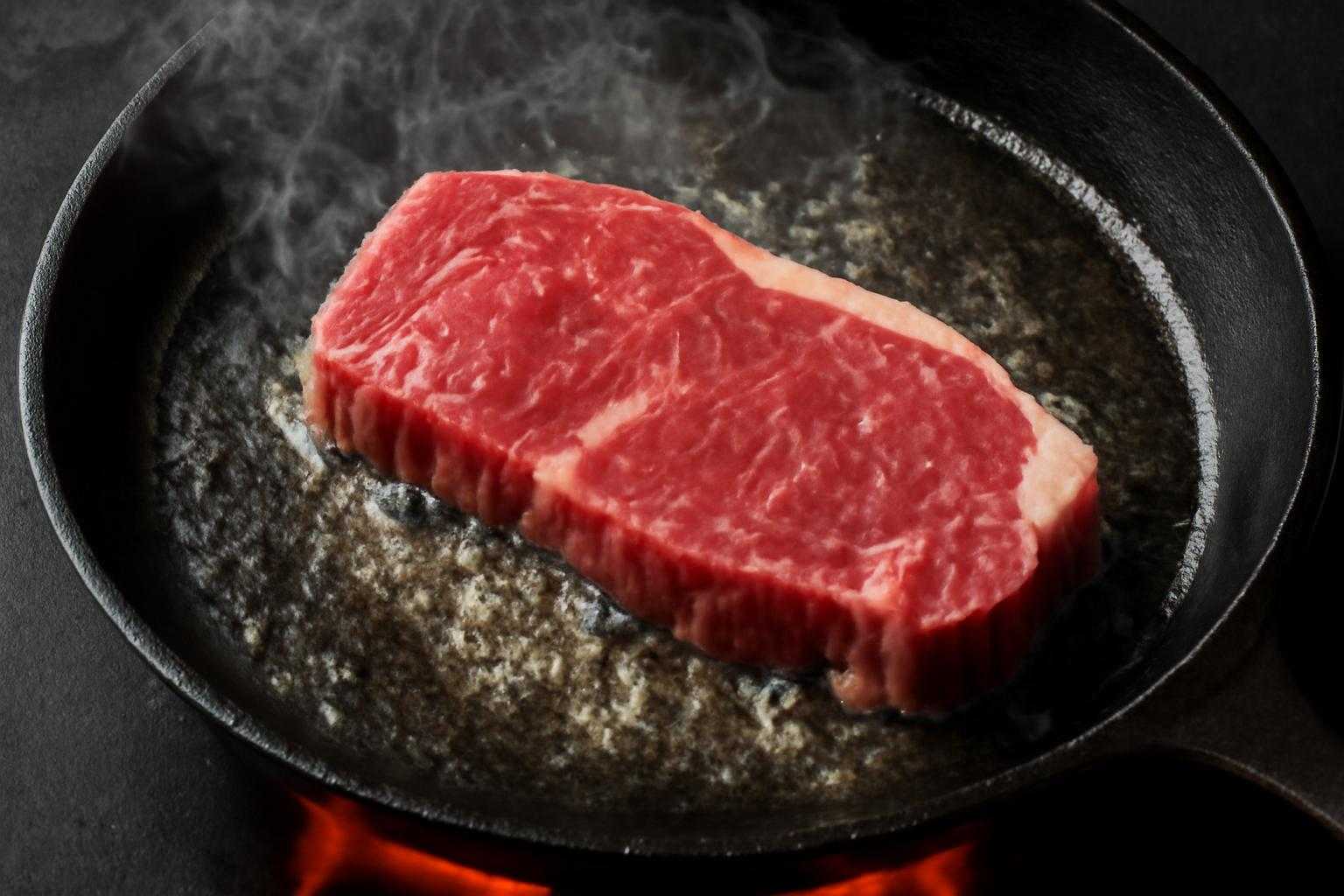 フライパンで焼く肉に火を入れているシーン